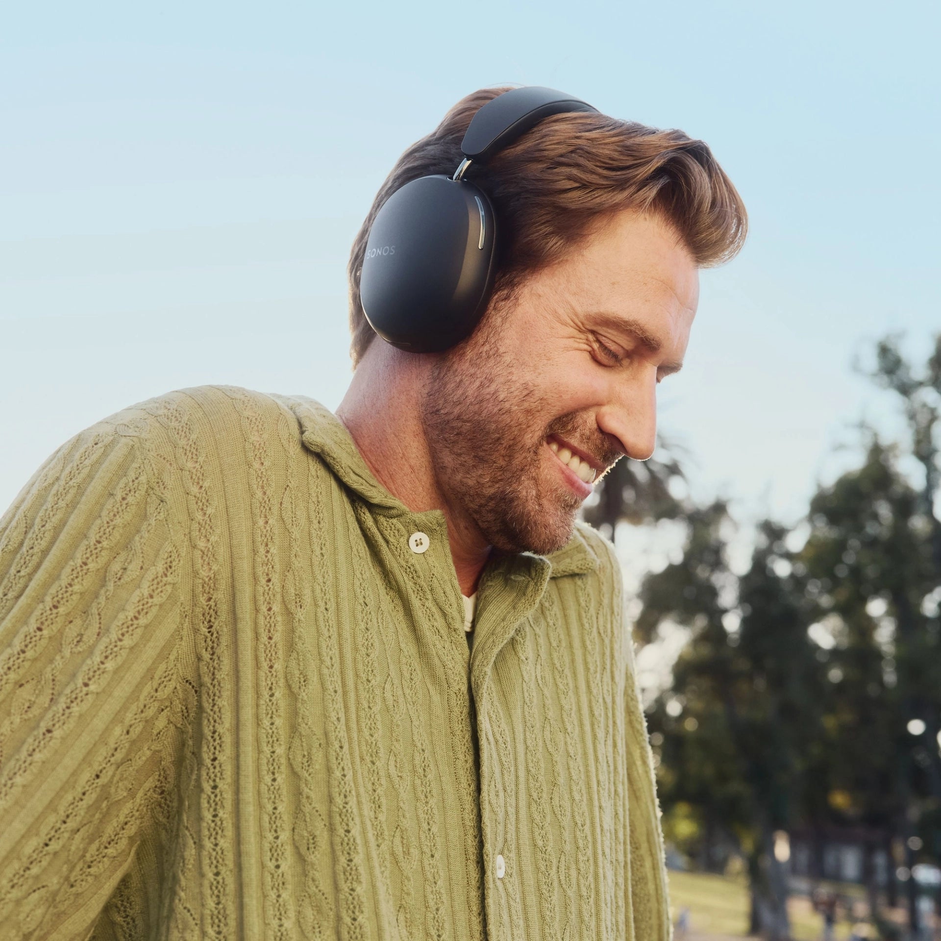 Lifestyle image of a male outdoors wearing Black Sonos Ace Headphones.