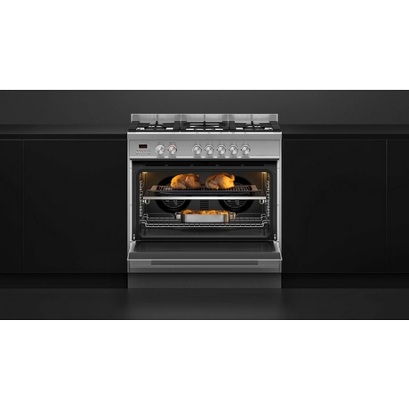 Stainless steel oven with food inside on a black kitchen background