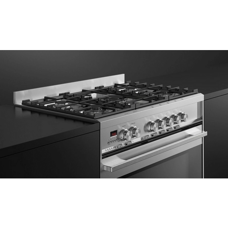 Stainless steel gas stove with black cooktop on a black background
