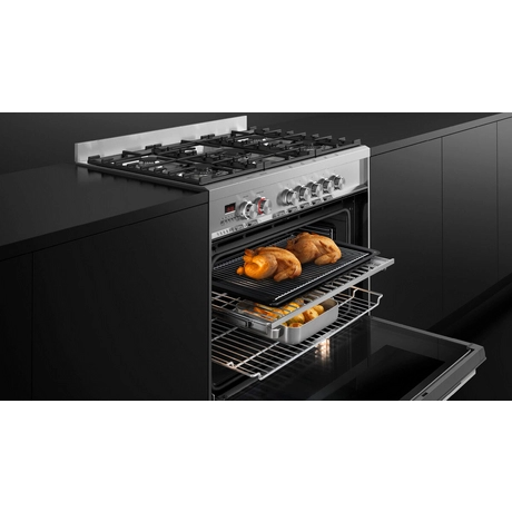 Stainless steel range cooker with open door showing roasted food inside.