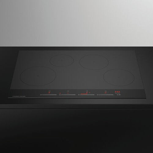 Black induction cooktop with four heating elements on a white background
