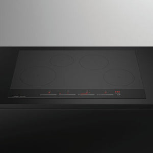 Black induction cooktop with four heating elements on a white background
