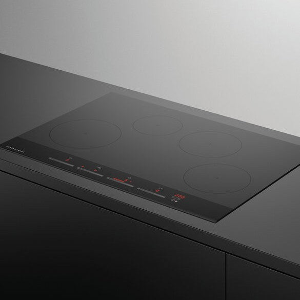Black induction cooktop on a gray countertop with a white background