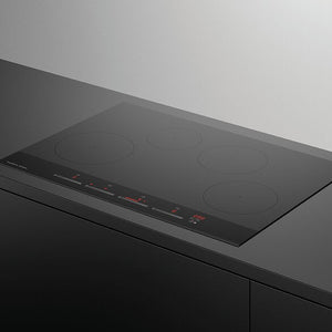 Black induction cooktop on a gray countertop with a white background