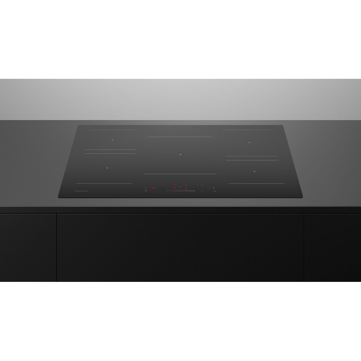 Black induction cooktop on a modern kitchen countertop with a metallic backsplash.