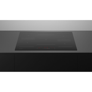 Black induction cooktop on a modern kitchen countertop with a metallic backsplash.