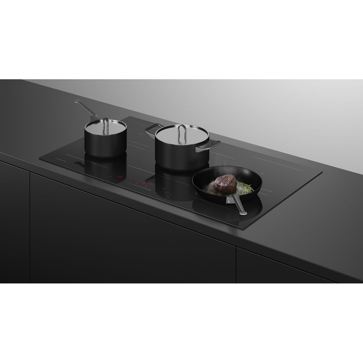 Black induction cooktop with pots and pans on a grey background